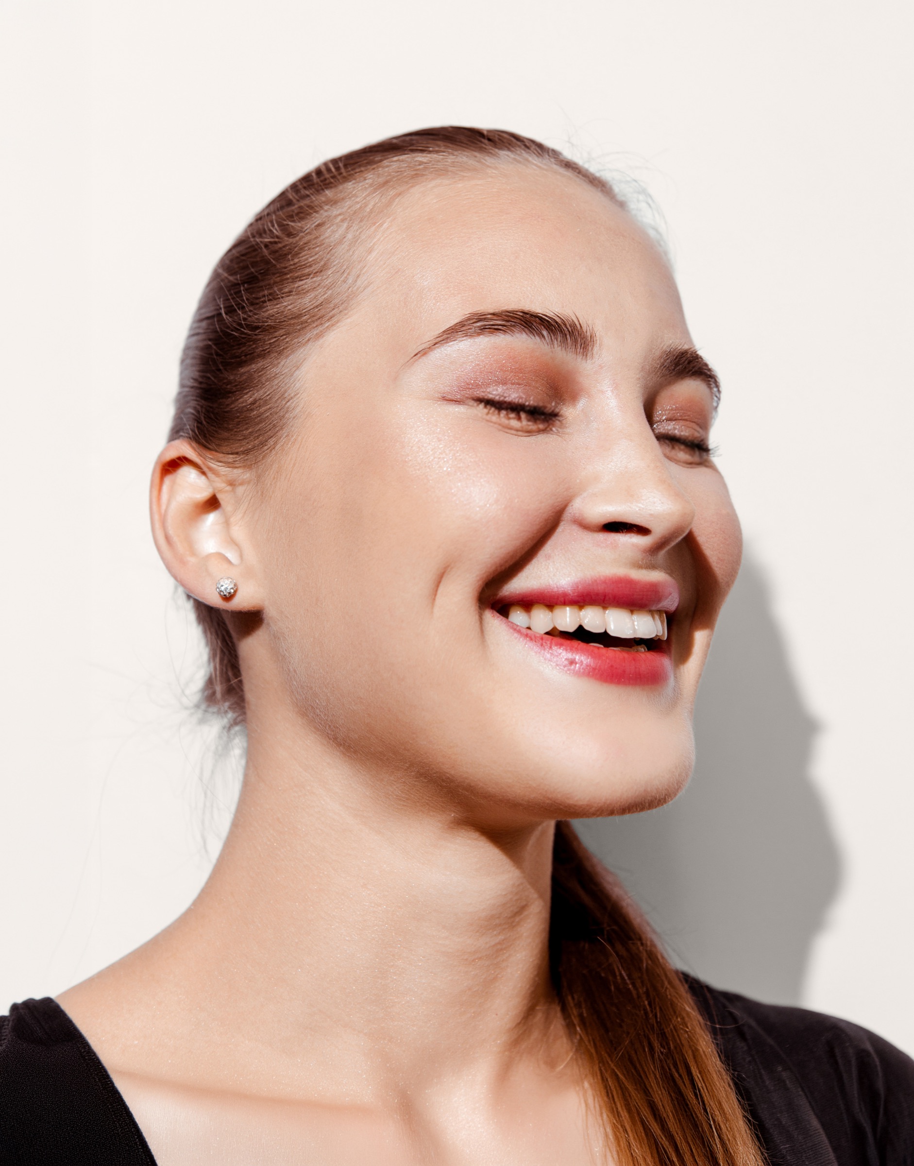 Smiling woman with her eyes closed and hair pulled back