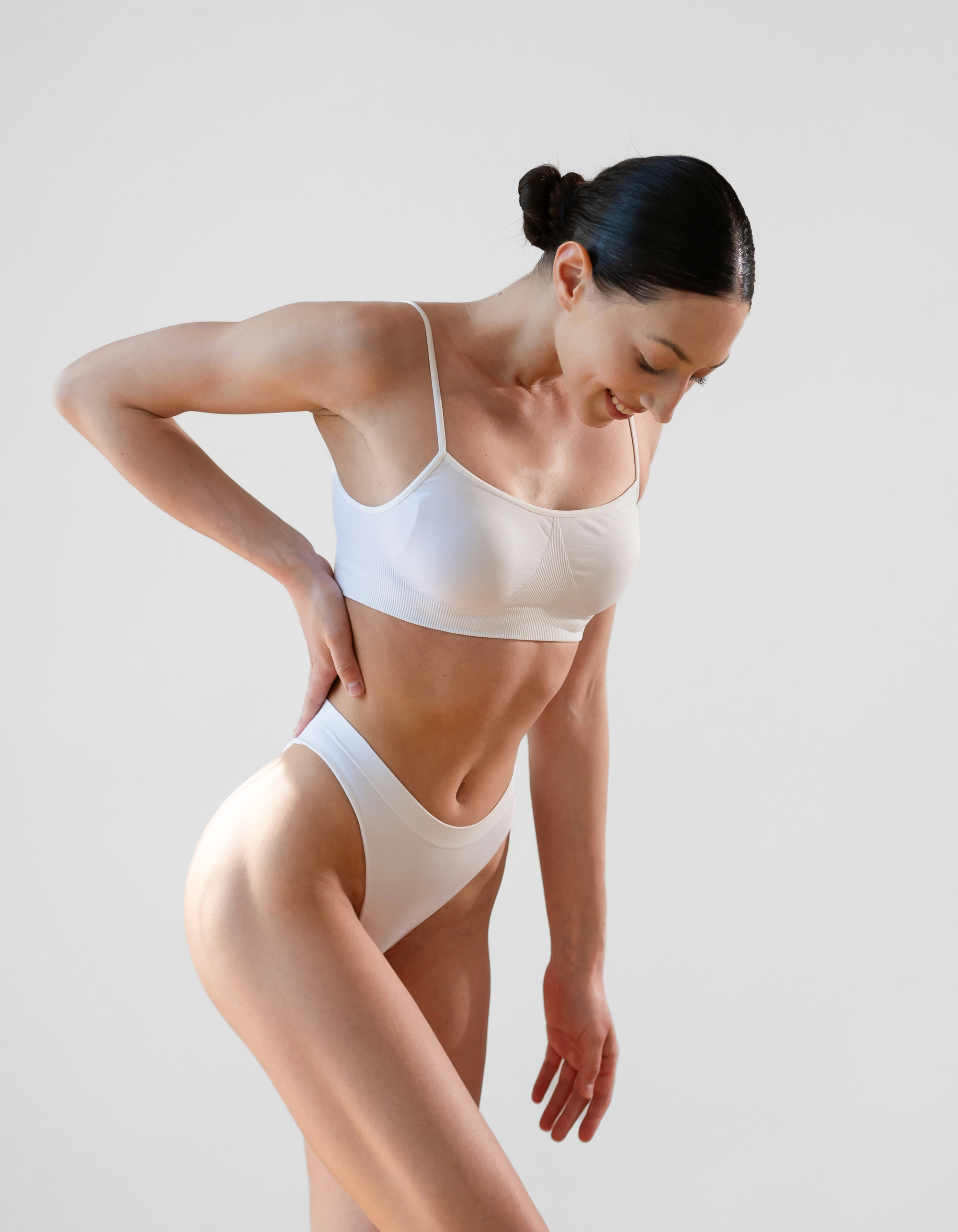 Woman in white underwear with a hand on her hip, looking down